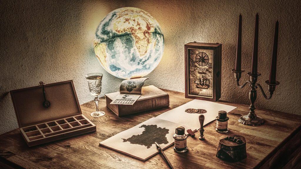 Vintage map, globe, candles on wooden desk