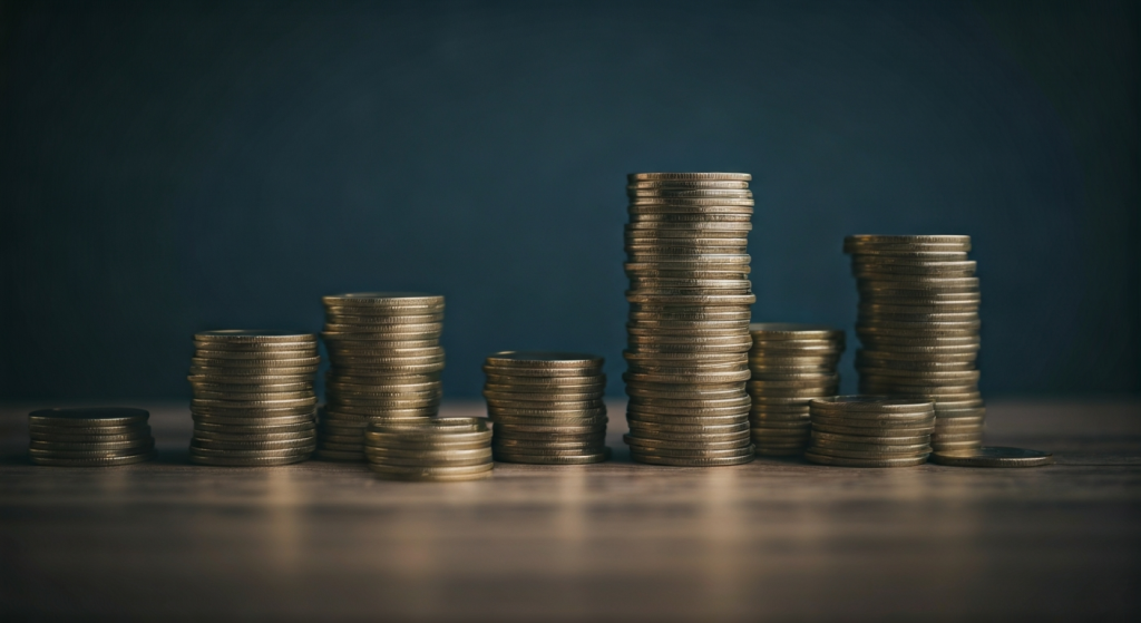 Stacks of coins on wooden surface.