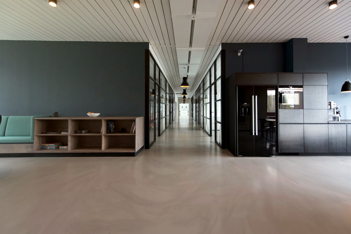 Modern office corridor with glass walls and lighting.